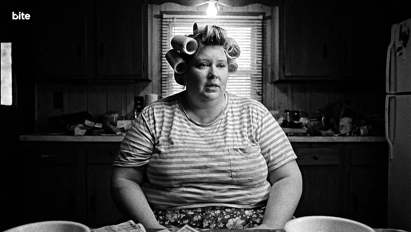 Woman with hair curlers in a dark kitchen