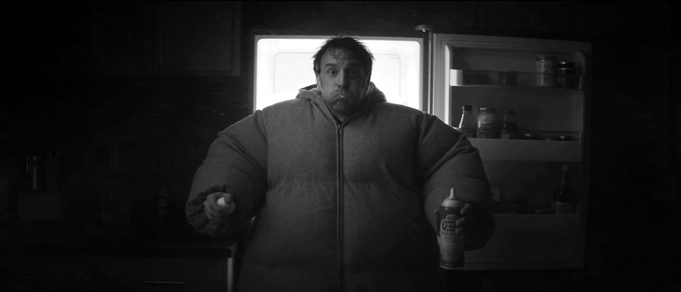 Man in a puffy jacket caught at an open fridge at night